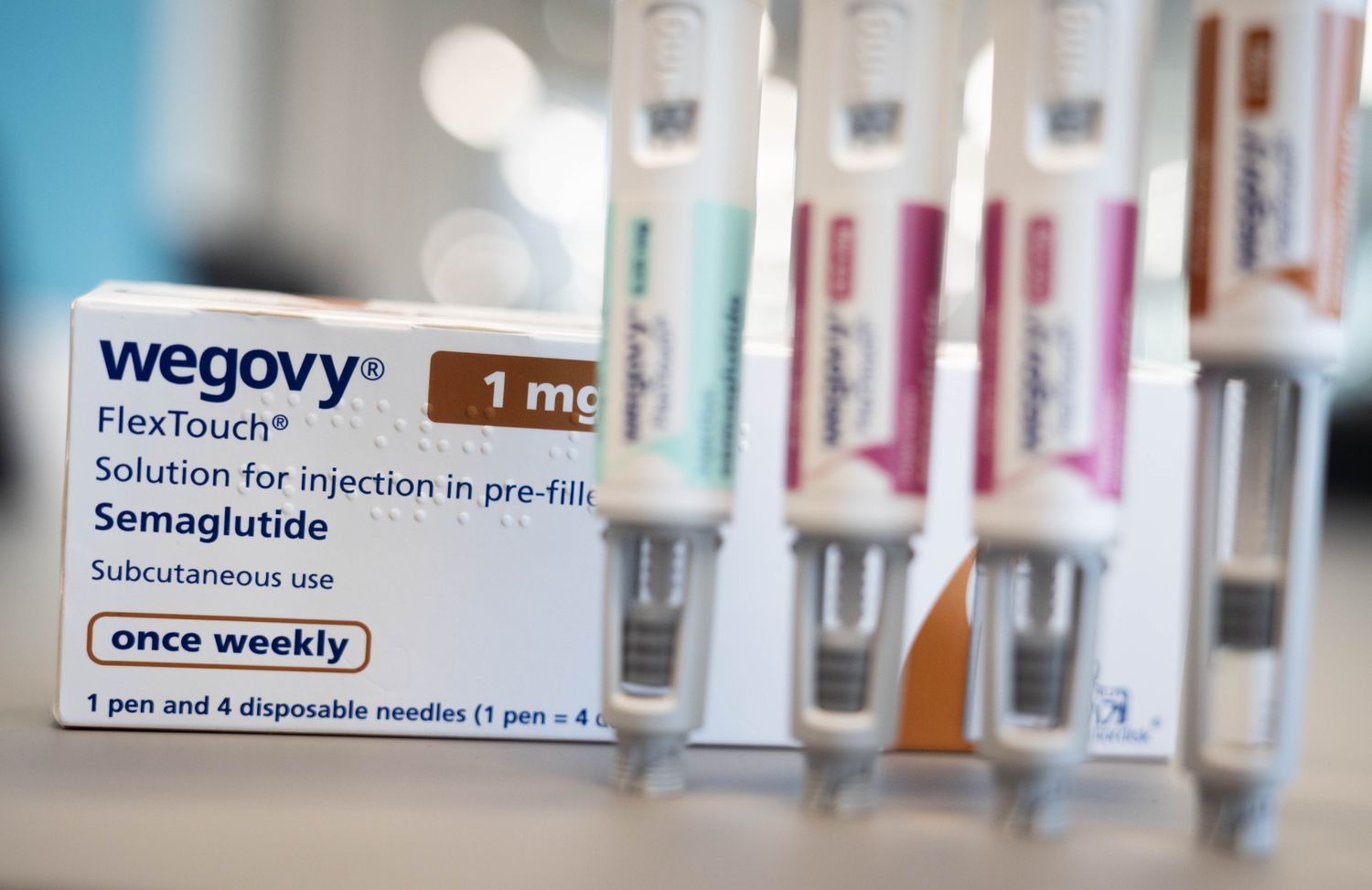 Four injector pens of the weight-loss drug Wegovy standing upright in front of a white box of the drug