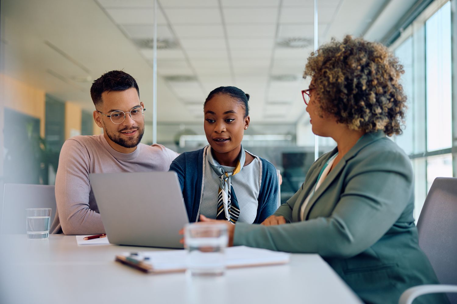 A young couple sit at a desk with a banker, opening a new account.