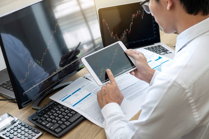 A midsection of businessman using technologies in office with data and charts.