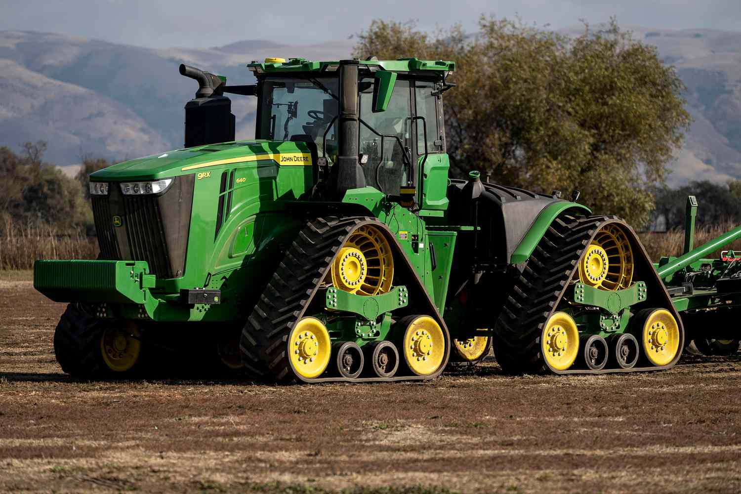 A green and yellow John Deere tractor drives through a field.