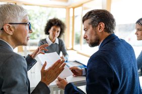 Women and men discussing paperwork at a table