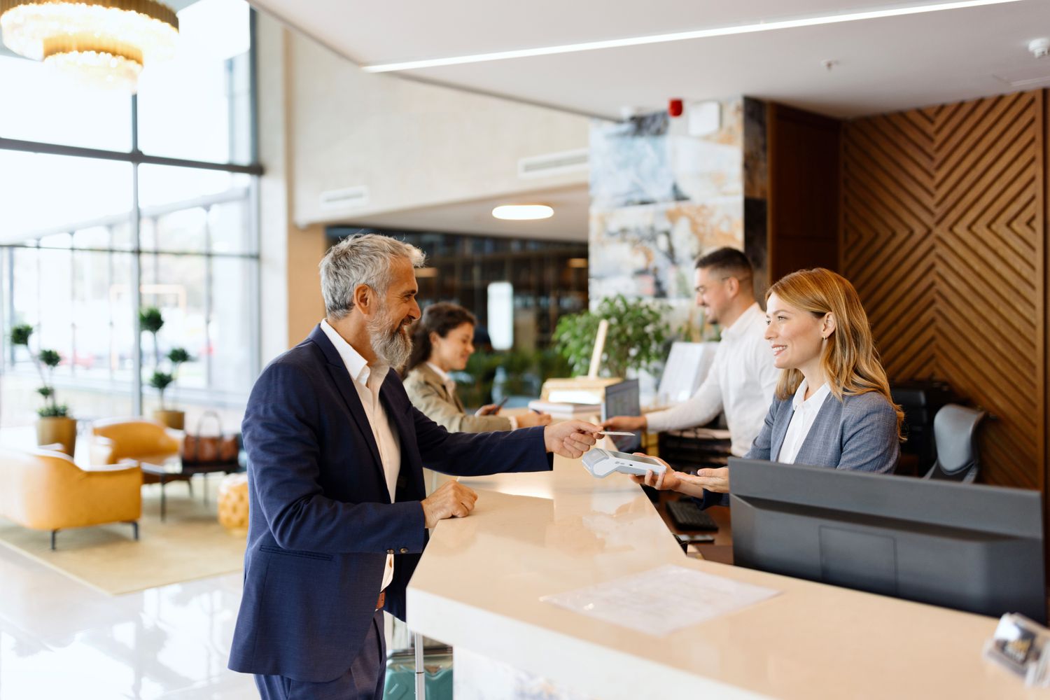 A customer paying with credit card at hotel reception to earn points and rewards.