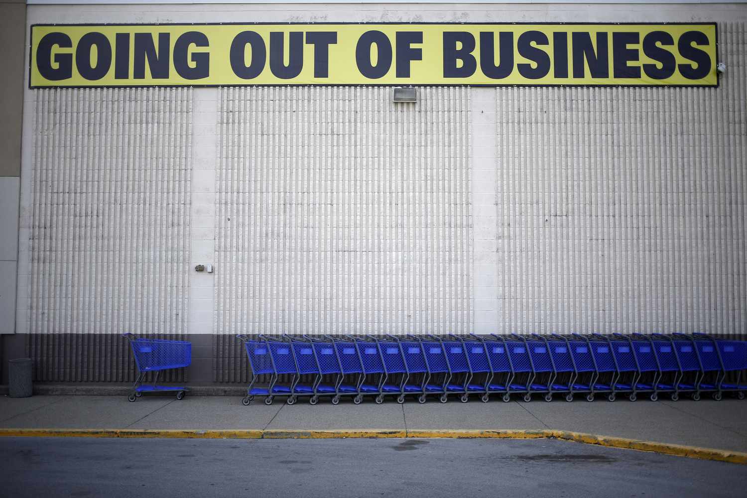 Going out of business sign on a building with shopping carts in front