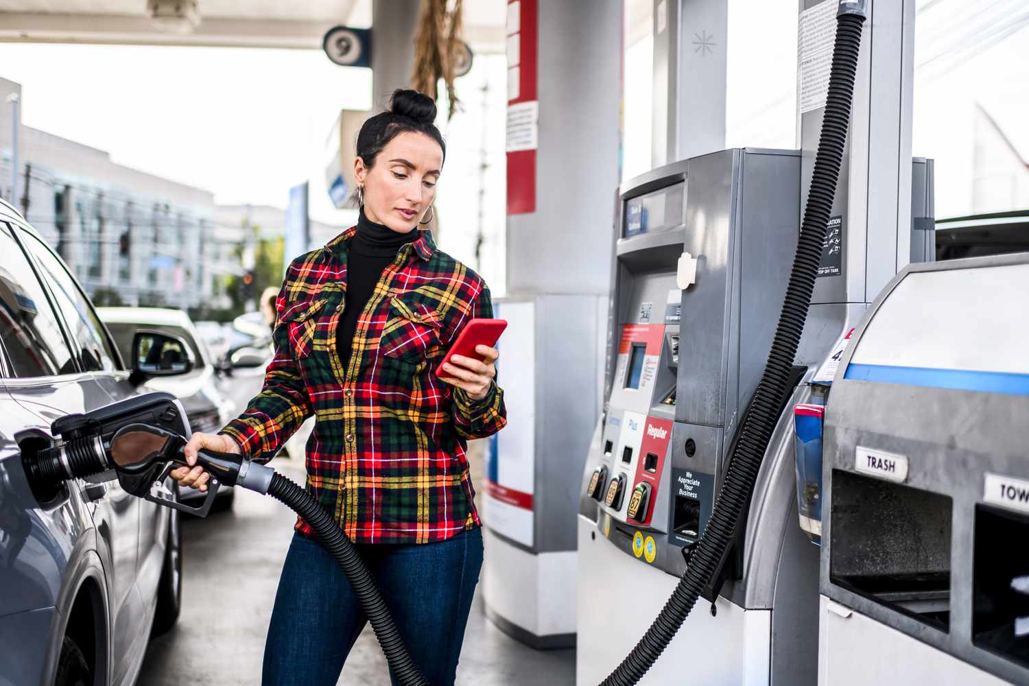 A salesperson looks at phone while pumping gas into a truck on the way to their next client call.