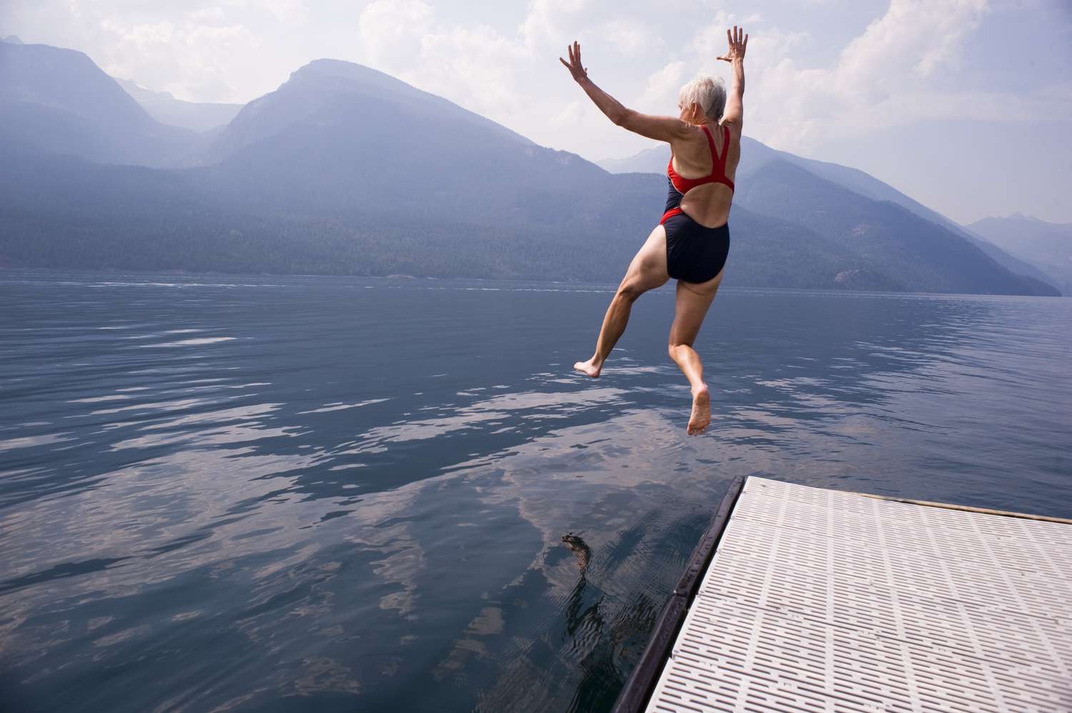 A person in a swimming suit leaping into a lake at a Canadian park.