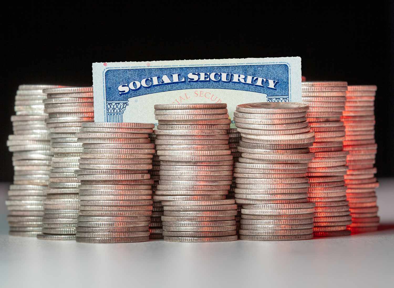Close-up of coins stacked by social security card on table against black background.