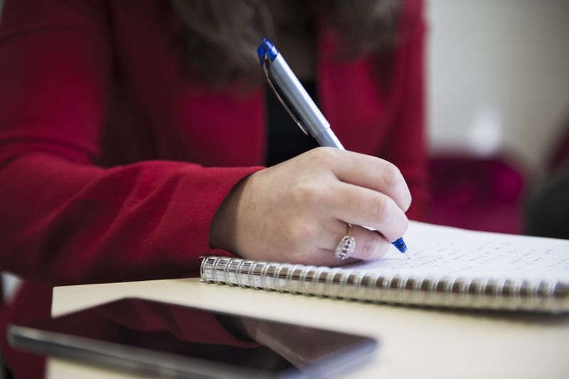 Close shot of woman writing in a notepad