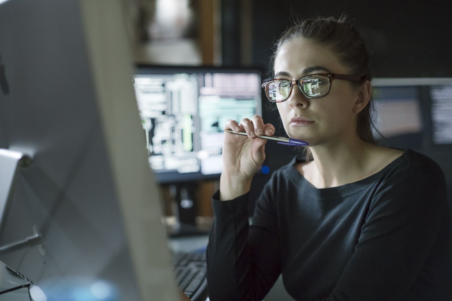 Woman in a darkened office looking at a computer. 
