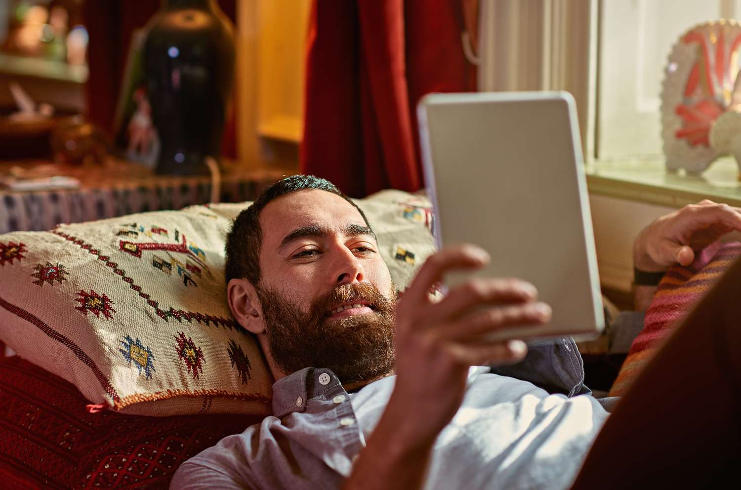 Man holding and reading an ereader while laying on a couch