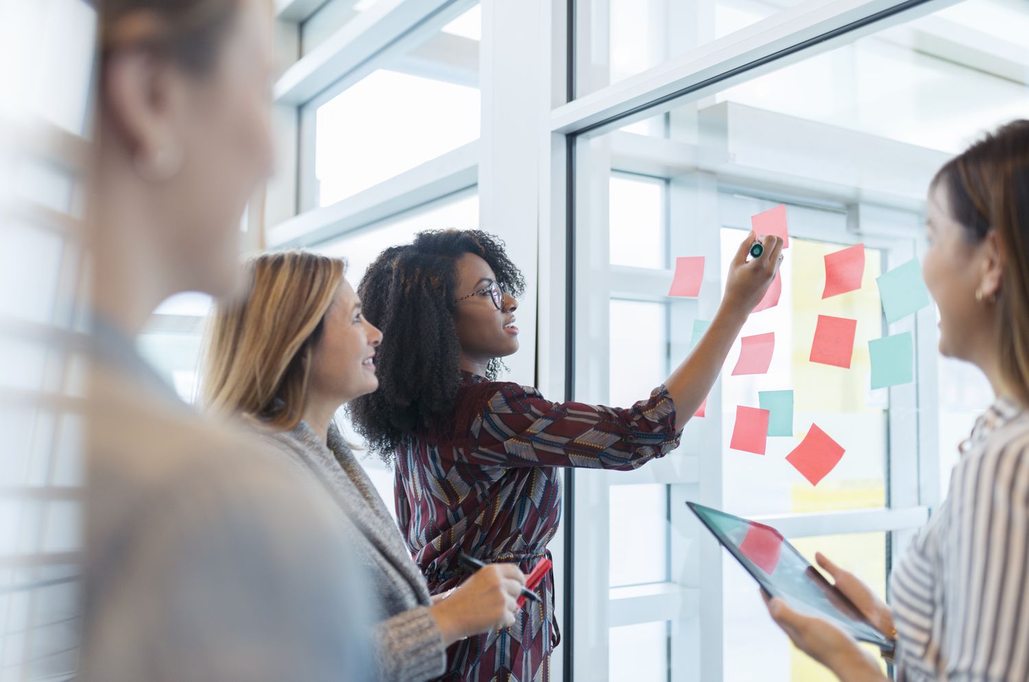 Four business partners use sticky notes to visualize how production and work will flow after they spin off a portion of the company.