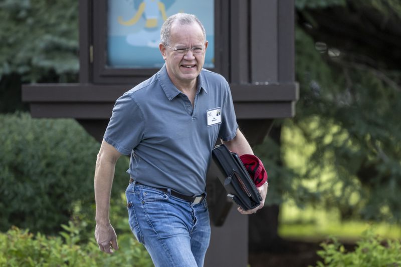Ted Weschler holding some files and a laptop as he is walking