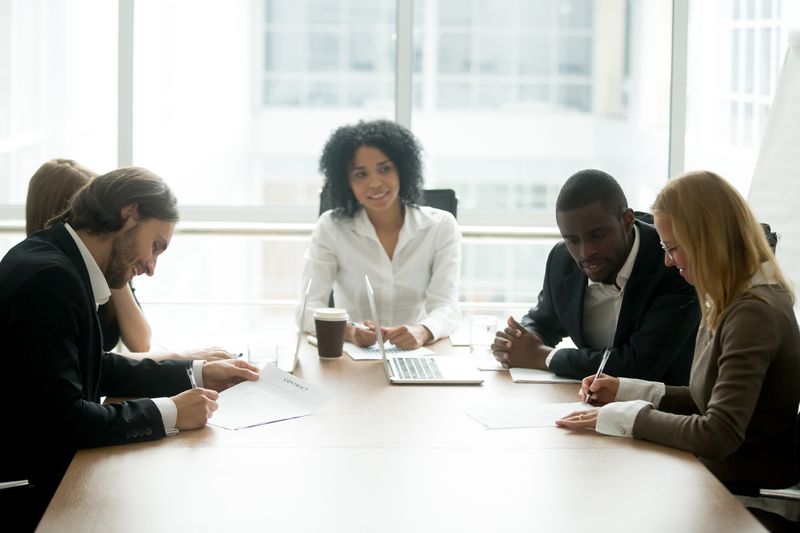 Businessman and businesswoman signing contracts with intermediary in between the two groups