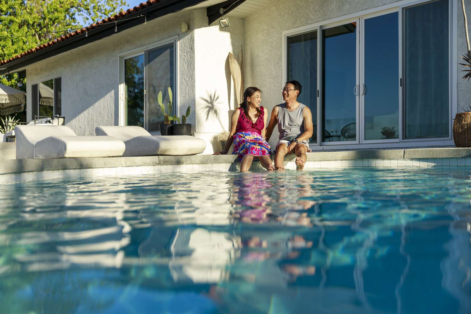 A couple spending time together by the pool of their vacation home.