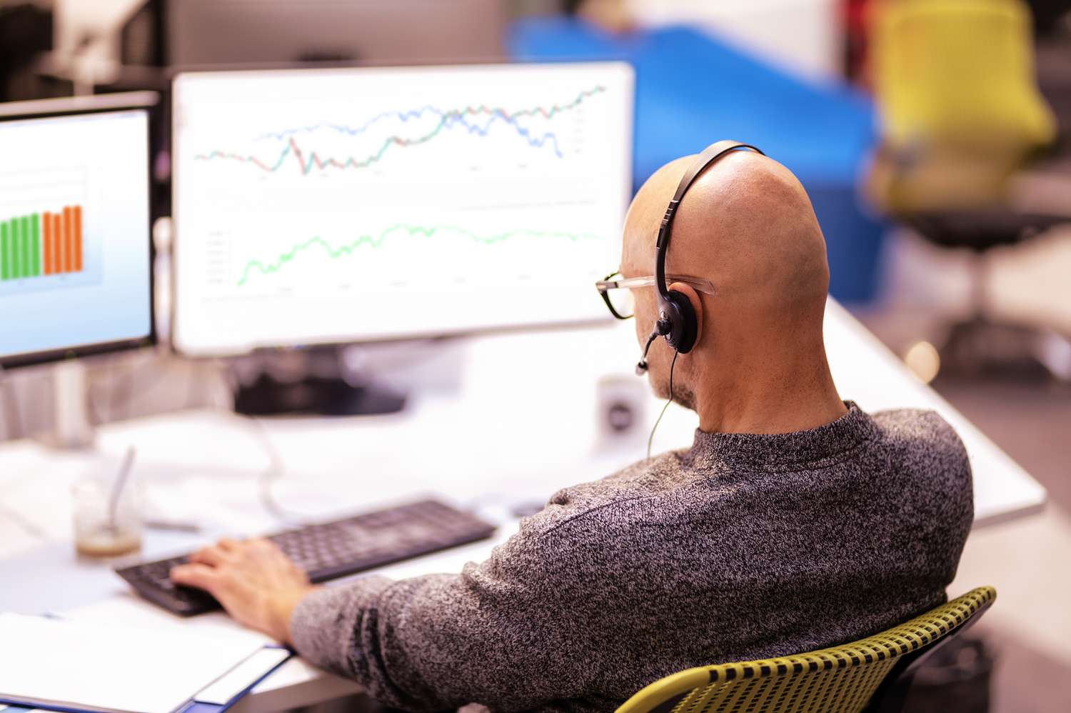 Stock broker who works for a market maker is performing trades on a computer and analyzing the stock market.