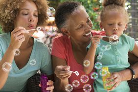 Multi-generational family blowing bubbles outdoors