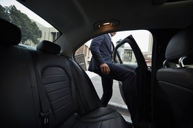 A businessman getting into backseat of exclusive cab.