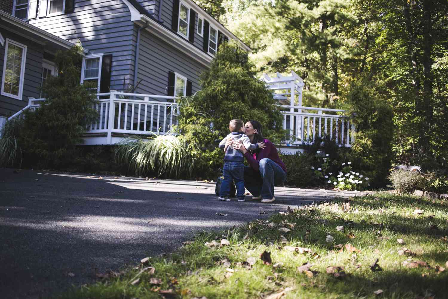 Mother kissing a toddler in front of their house which they got through offset mortgage.