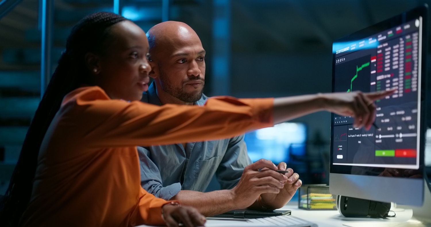 An analyst uses a computer monitor to point out a potential price support for a stock they are following to their colleague.