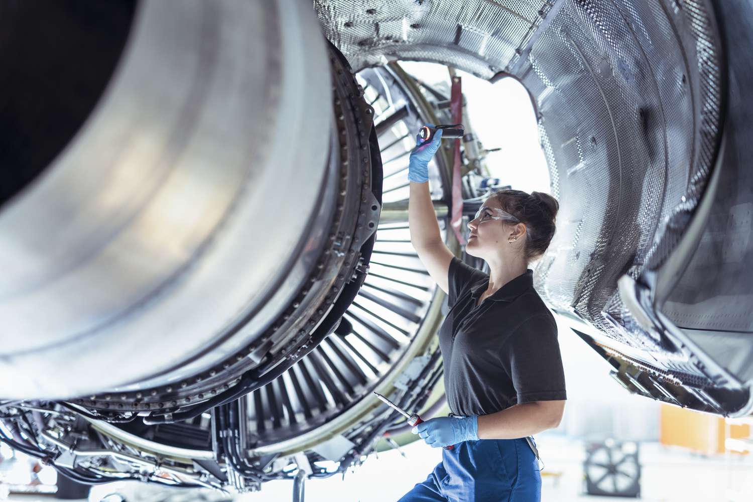 A woman works on a jet engine. 