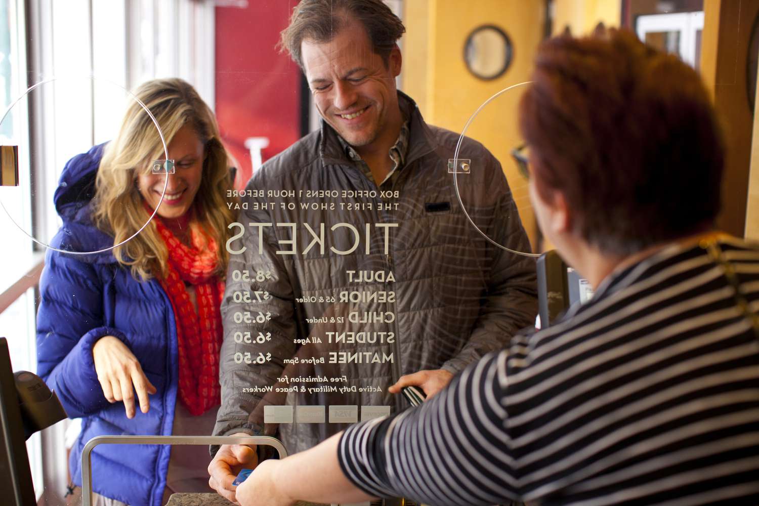 A couple buys tickets at a theater. 