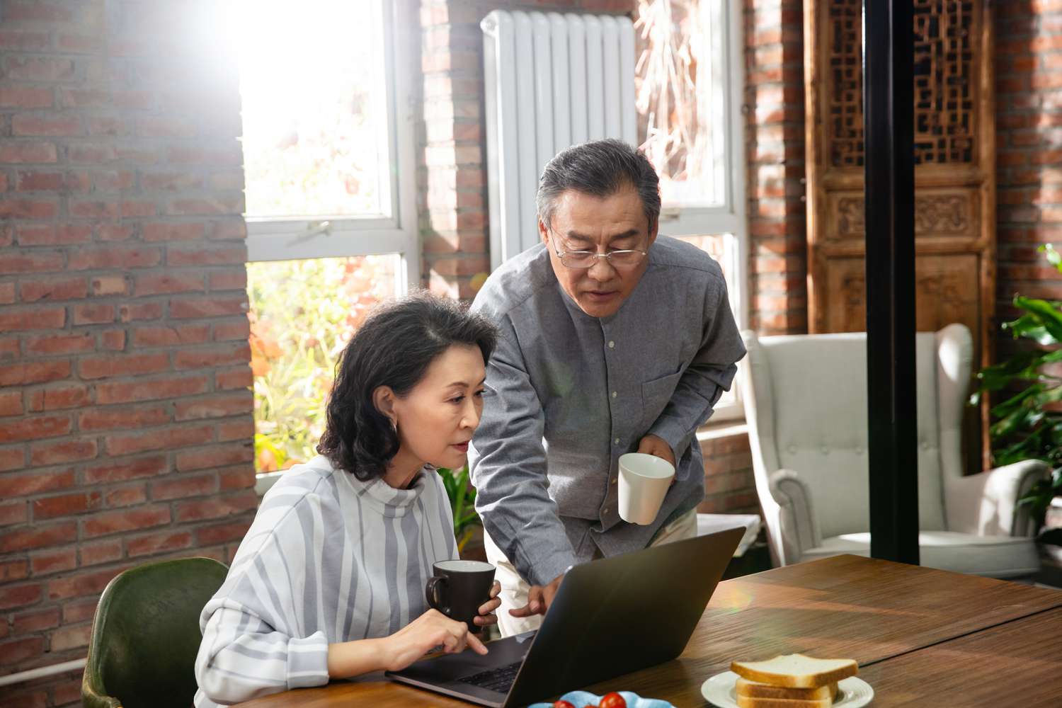 Older couple with coffee cups and a laptop