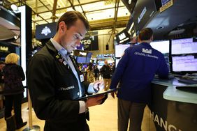 A trader looks at a tablet on the floor of the New York Stock Exchange
