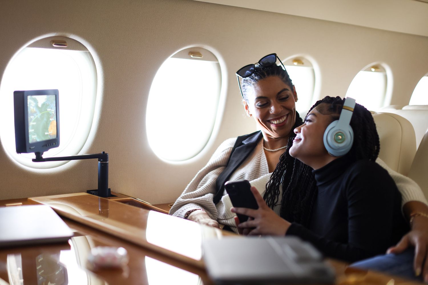 Woman and daughter setting next to each other on private jet. 