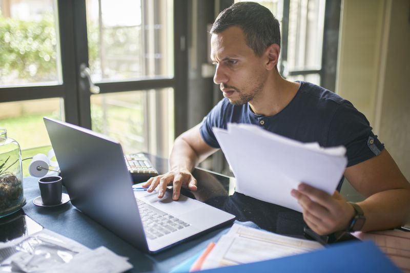Man preparing his taxes on laptop in a home office.