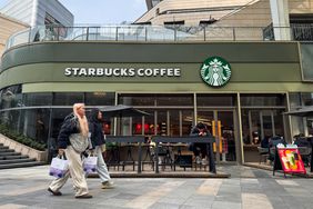 Pedestrians carrying shopping bags walk past a Starbucks Coffee storefront in a modern shopping district on Jan. 26, 2025, in Chongqing, China
