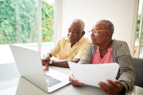 Older couple working together on laptop at home