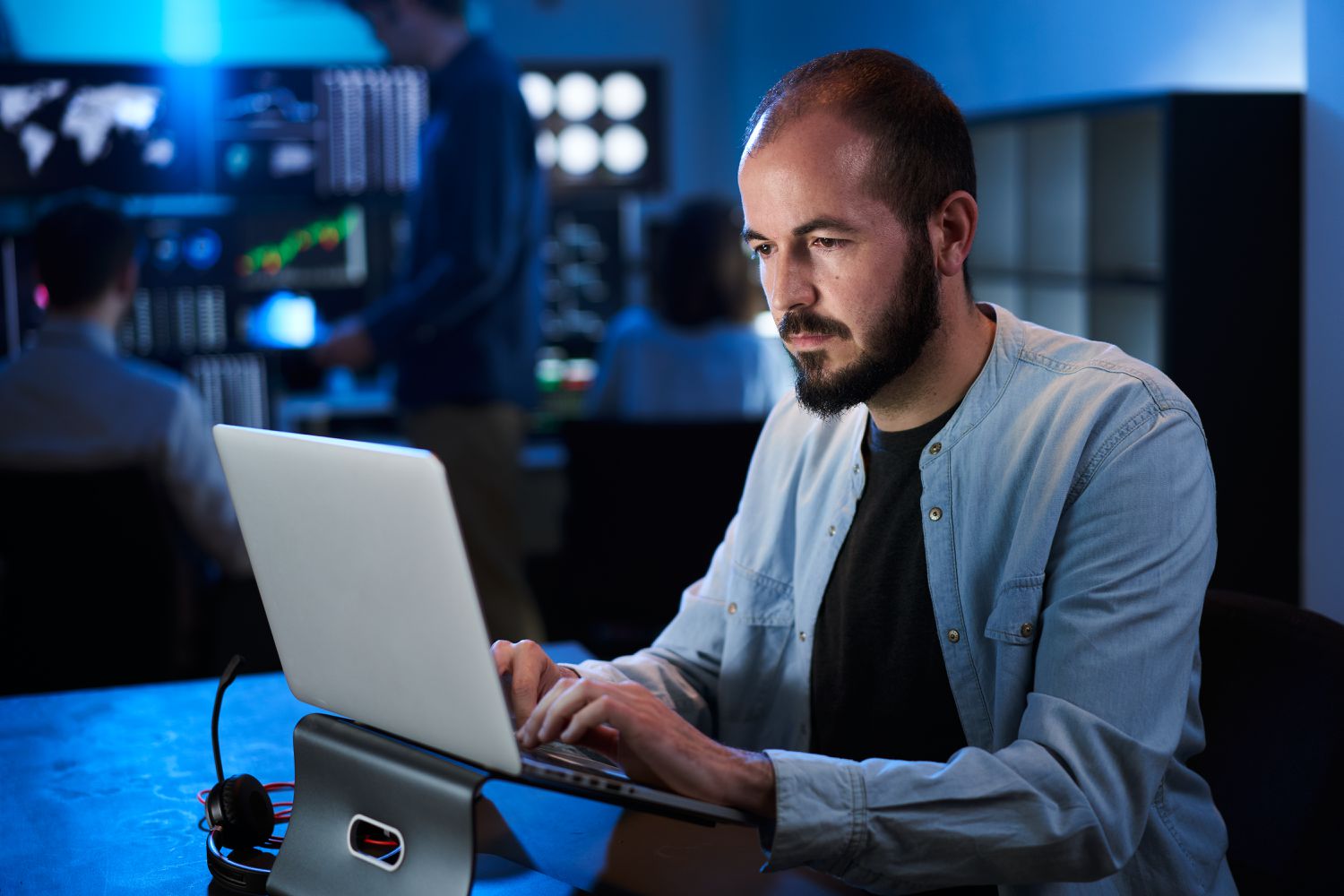 Man in a darkened room working on a laptop