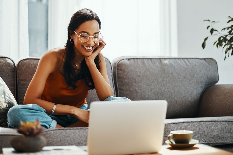 Shot of a young woman using a laptop on the sofa at home
