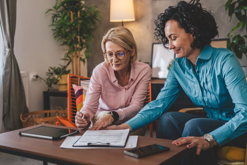 Two women looking over a document together.