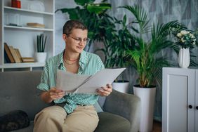 Person reading a document seated on a couch.
