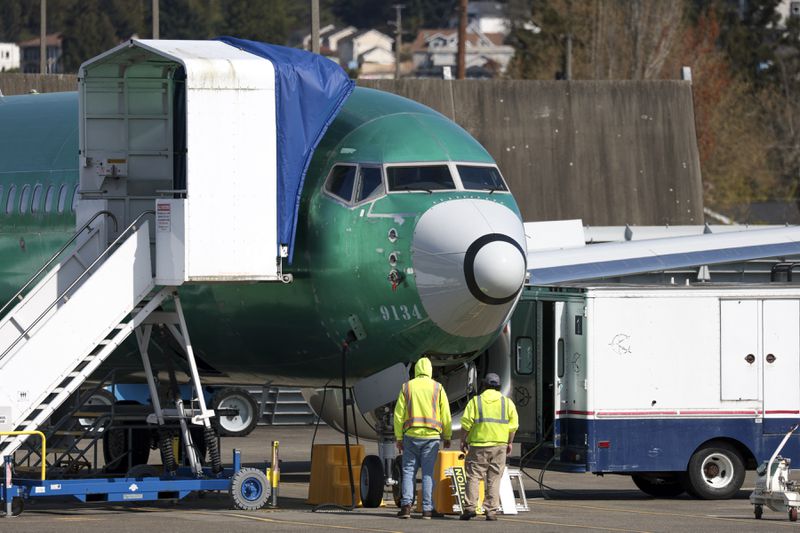 Workers stand in front of a Boeing 737 aircraft at Boeing's Renton factory in Renton, Washington, on April 15, 2025.