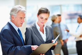 A man and a woman review documents in a folder