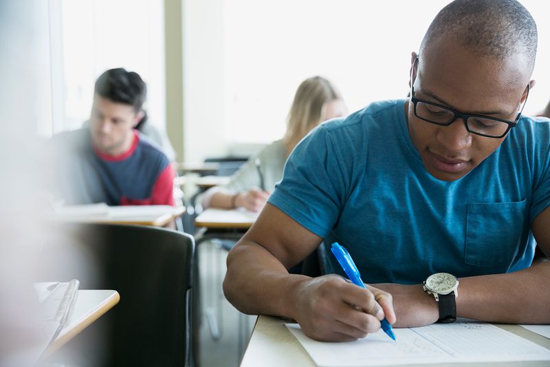 Focused college students taking exam in classroom.