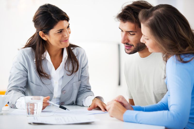 A financial consultant presents bank investments to a young couple.