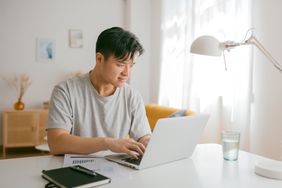 A man sits at a desk with a laptop