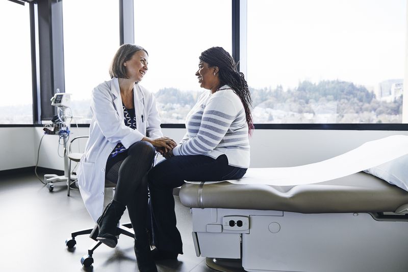 A female doctor talking to a female patient in a hospital room