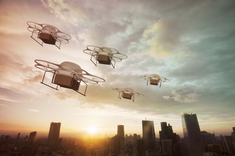five drones flying at sunset with a skyline behind them
