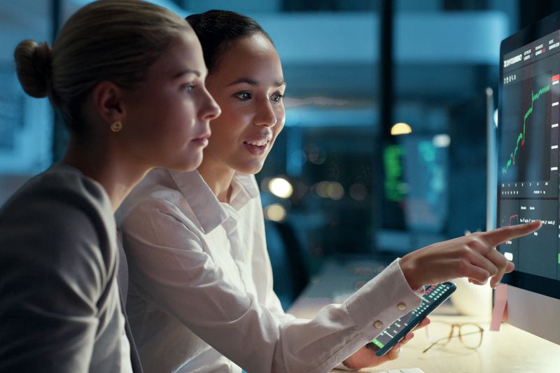 Professionals looking at financial data on a computer screen.