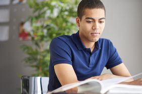 A student studying a book on his desk.