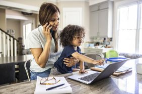 Woman on the phone working from home with her toddler on her lap.