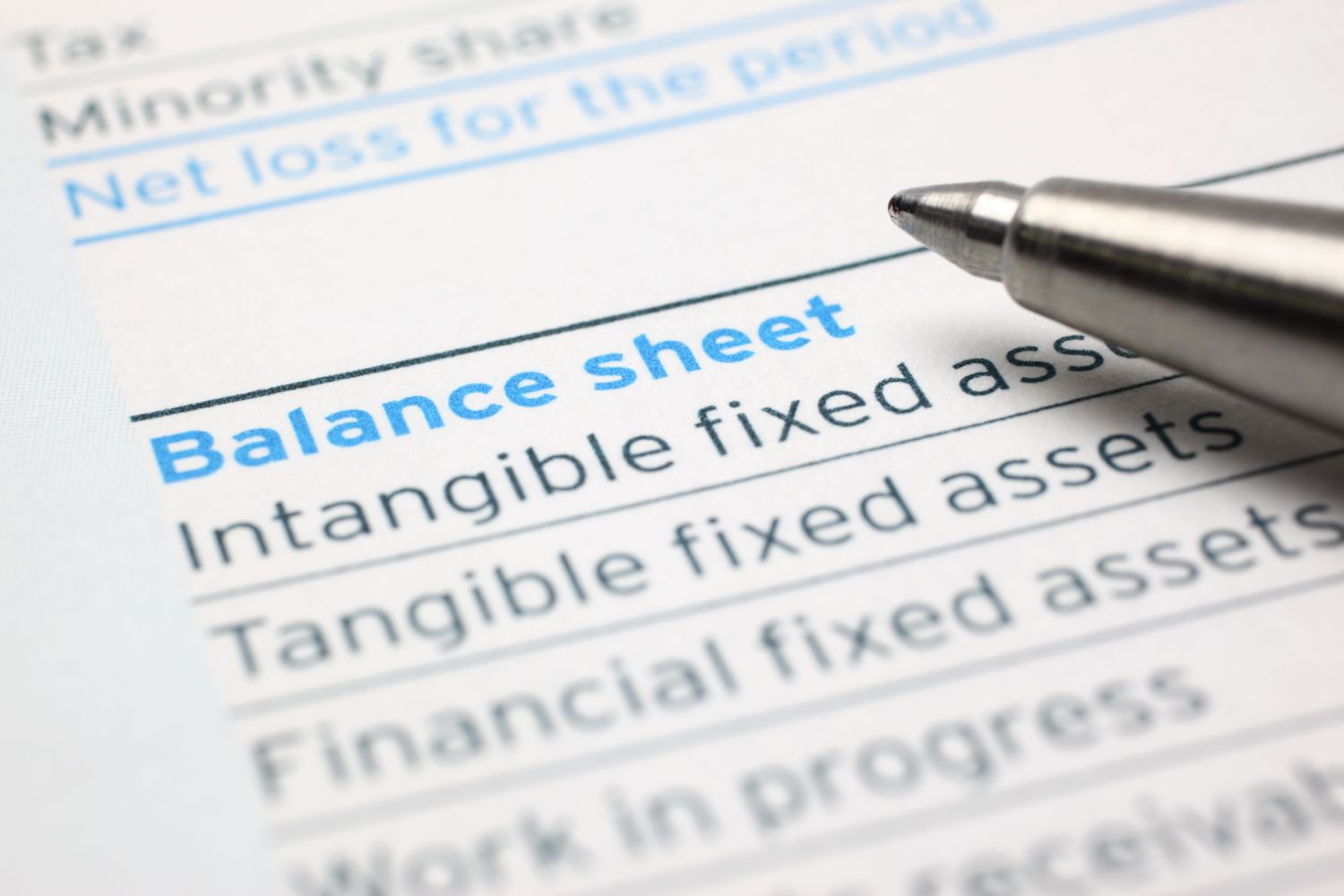 A close-up image of a pen and a balance sheet