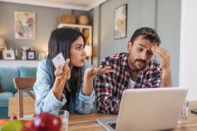 A concerned couple discussing while using a laptop at home