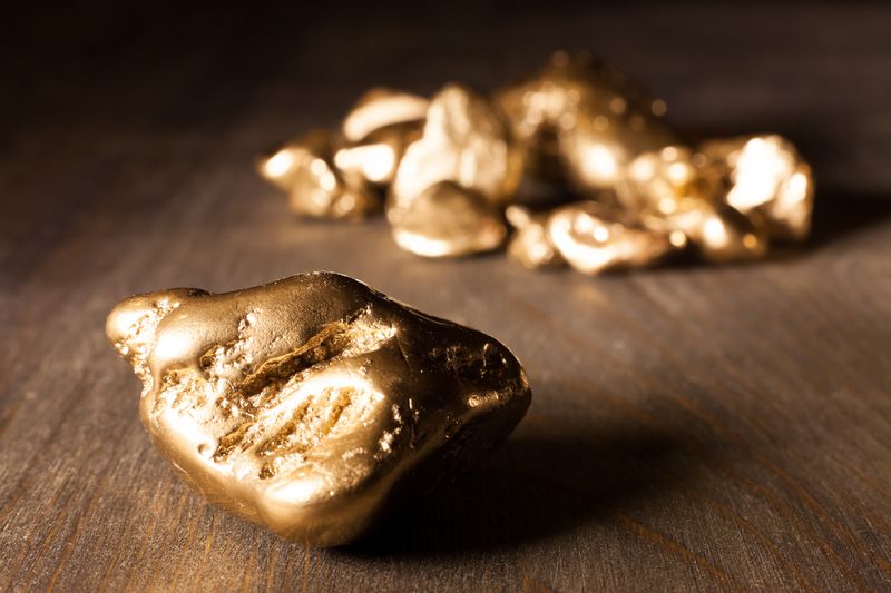Several large gold nuggets on a wooden table