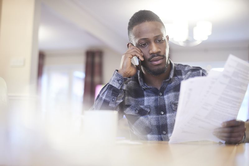 A young man reviews a car insurance policy over the phone.