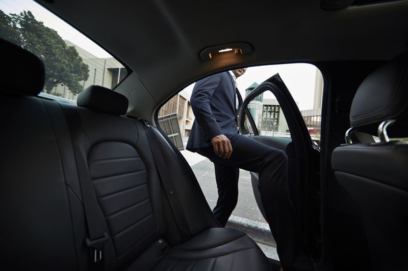A businessman getting into backseat of exclusive cab.
