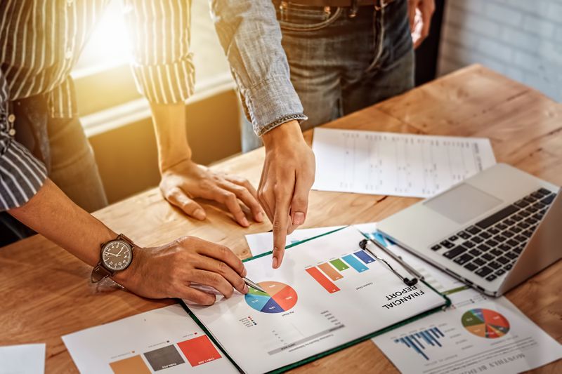young business man hand holding pen and partner pointing graph
